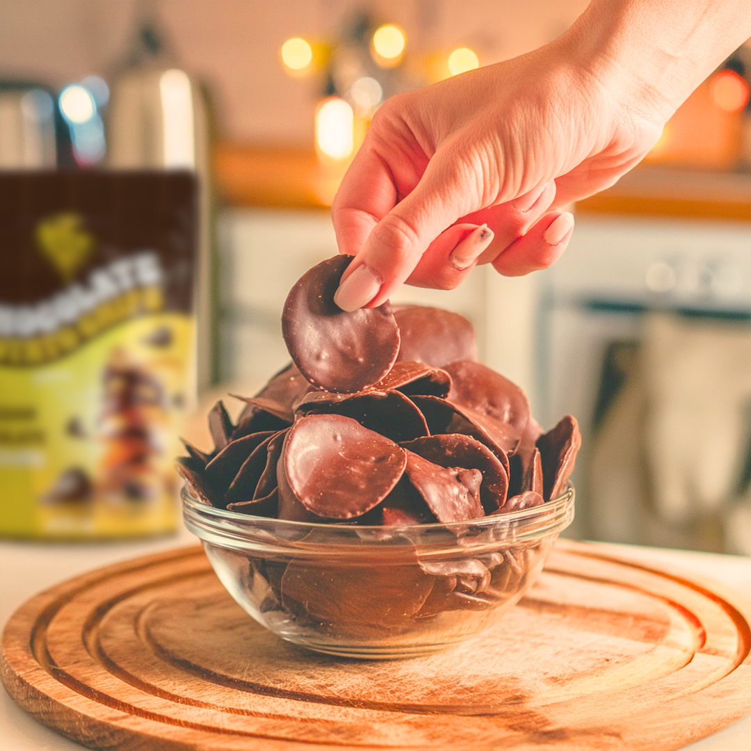Hand picking a belgian chocolate coated potato chip from a glass bowl
